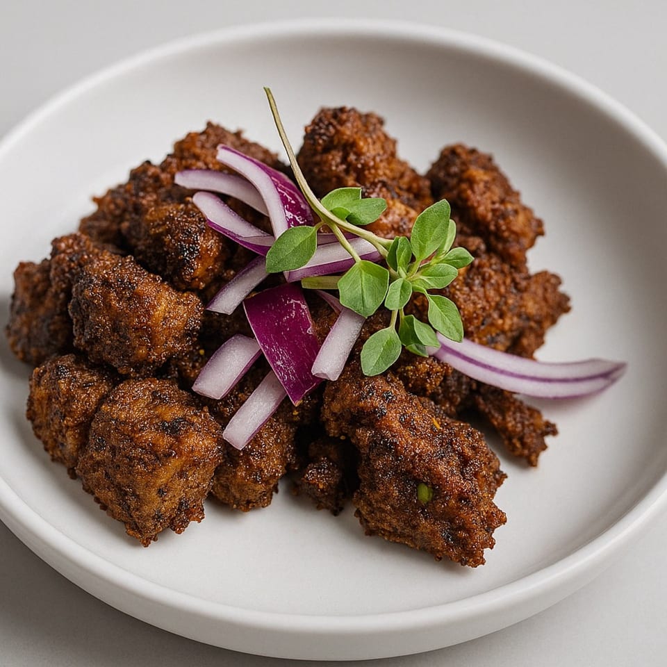 Aditi Indian Dining's chicken tikka, garnished with red onion slices and fresh herbs on a white plate.