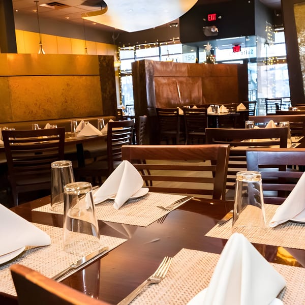 Aditi Indian Dining interior with set tables, dark wood chairs, and warm lighting.