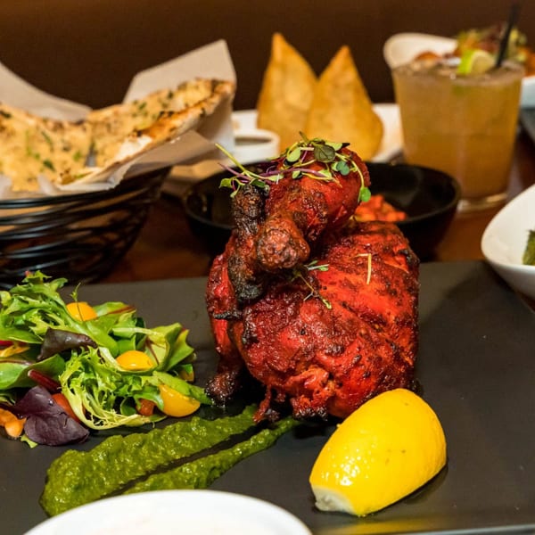 Aditi Indian Dining's Tandoori Chicken, a whole roasted chicken, with a side salad and lemon.