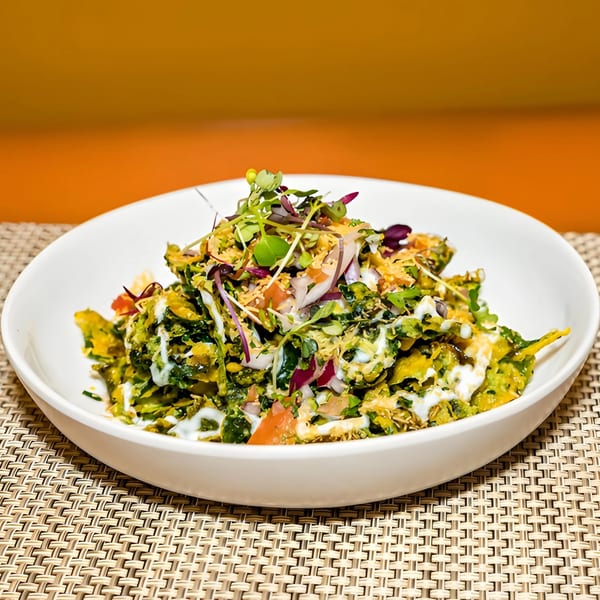 Aditi Indian Dining's Indian salad with green vegetables, white sauce, and microgreens in a white bowl.