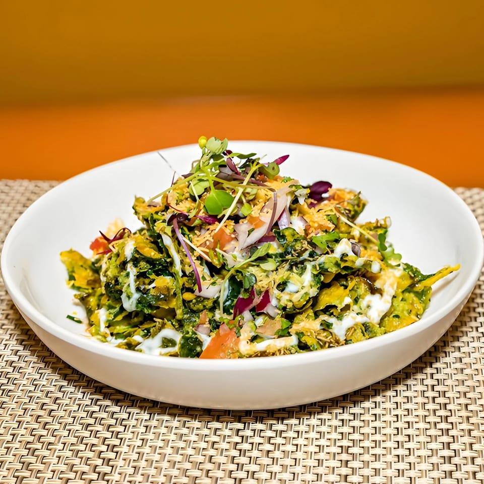 Aditi Indian Dining's Indian salad with green vegetables, white sauce, and microgreens in a white bowl.