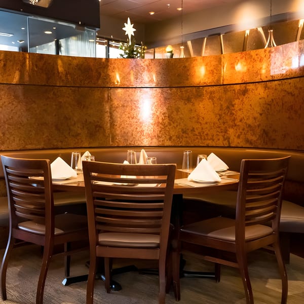 Aditi Indian Dining's cozy booth seating with a round table set with white napkins and glasses.